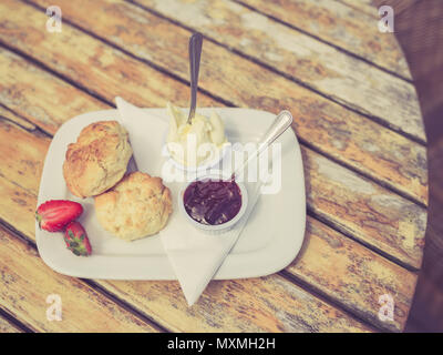 Vintage photo de filtré avec un thé à la crème et de la confiture de scone sur une table Banque D'Images