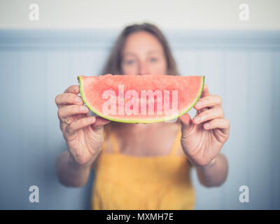 Une jeune femme est maintenant une tranche de melon d'eau Banque D'Images
