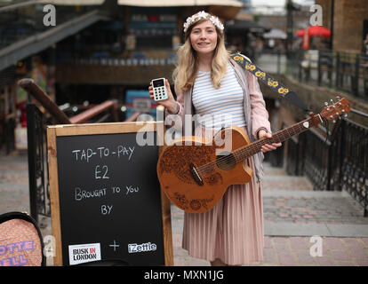 Musicien ambulant Charlotte Campbell effectue en marché de Camden, au nord de Londres, que Kate Jones, directeur de programme à Busk à Londres, les regarde. Londres a lancé le premier système de paiement sans contact pour les amuseurs publics en collaboration avec l'entreprise de technologie iZettle. Banque D'Images