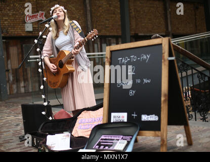 Musicien ambulant Charlotte Campbell effectue en marché de Camden, au nord de Londres, que Kate Jones, directeur de programme à Busk à Londres, les regarde. Londres a lancé le premier système de paiement sans contact pour les amuseurs publics en collaboration avec l'entreprise de technologie iZettle. Banque D'Images