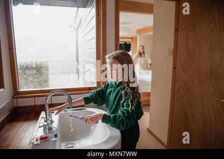 Petite fille vêtue d'un uniforme scolaire se brosser les dents avant d'aller à l'école. Banque D'Images