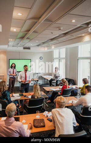 Mâle mature adult businessman donnant une présentation à l'avant de la salle pendant que tout le monde est assis et d'écouter. Banque D'Images
