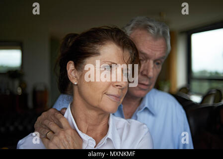 Couple de personnes âgées ensemble art home, le mari est vu réconfortant sa femme dans une étreinte aimante après avoir reçu une mauvaise nouvelle Banque D'Images