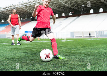 Teenage Boy Kicking Ball Banque D'Images