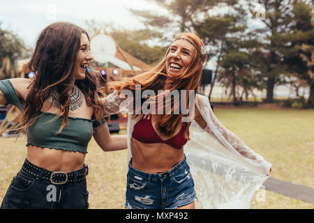 Deux jeunes femmes de sourire et avoir un grand temps au festival de musique. Girl friends dans l'usure de l'été en profitant de la musique. Banque D'Images