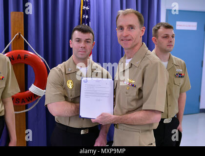161201-N-OK605-021 MISAWA, Japon (déc. 1, 2016) Maître de 1re classe Josh Riendeau, attribué à Naval Air Facility Misawa Security Service, de Weeki Wachee, en Floride, reçoit son frocking lettre du capitaine Keith Henry, Naval Air Facility Misawa son commandant, au cours d'une cérémonie à frocking NAF Misawa. Riendeau a été avancé à la vitesse de 1re classe Officier marinier. (U.S. Photo de la marine du Maître de 2e classe Samuel Weldin/libérés) Banque D'Images