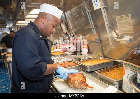 161124-N-MW990-062 BASE NAVALE de Changi, Singapour (24 novembre 2016) Maître de 1re classe Jonathan Lewis sculpte la Turquie pour le dîner de Thanksgiving à bord du USS Coronado (LCS) 4. En ce moment à tour de déploiement à l'appui de l'Asia-Pacific rééquilibrer, Coronado est un navire de guerre rapide et agile sur mesure pour patrouiller les eaux littorales de la région et travailler à coque coque avec des marines, partenaire fournissant 7e flotte avec les capacités flexibles dont elle a besoin maintenant et dans l'avenir. (U.S. Photo de la marine du Maître de 2e classe Michaela Garrison/libéré) Banque D'Images