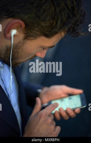Close up d'un jeune homme d'affaires bien habillés dans la ville tôt le matin, la lumière du jour, l'aube d'une nouvelle journée avec de nouvelles occasions de porter des écouteurs Banque D'Images