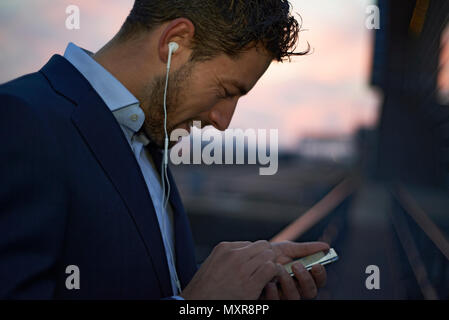 Close up d'un jeune homme d'affaires bien habillés dans la ville tôt le matin, la lumière du jour, l'aube d'une nouvelle journée avec de nouvelles occasions de porter des écouteurs Banque D'Images
