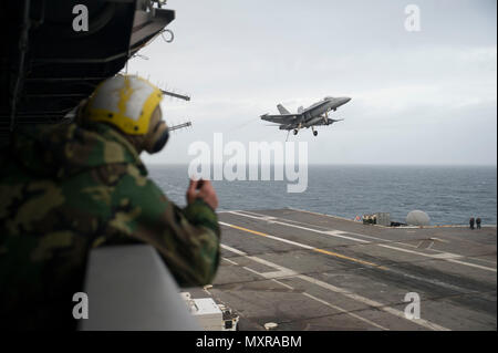 161129-N-YW501-024 OCÉAN ATLANTIQUE (nov. 29, 2016) Un marin montres un F/A-18 Hornet, attribué aux Romains de Strike Fighter Squadron (VFA) 106, voler au-dessus du pont d'envol du porte-avions USS George Washington (CVN 73) pendant les opérations de vol. George Washington, homported à Norfolk, est en cours la réalisation des qualifications de l'opérateur dans l'océan Atlantique. (U.S. Photo par MARINE MATELOT Jamin Gordon) Banque D'Images