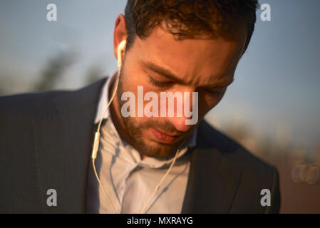 Portrait d'un jeune homme bien habillé d'affaires portant des bourgeons de l'oreille il s'agit de parler au téléphone Banque D'Images