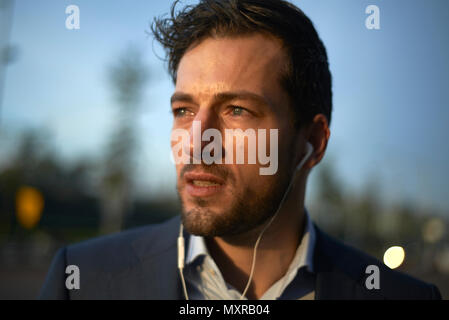 Portrait d'un jeune homme bien habillé d'affaires portant des bourgeons de l'oreille il s'agit de parler au téléphone Banque D'Images