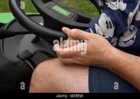 Père et fils : un père laisse son fils de 5 ans à diriger le tracteur-tondeuse qu'il coupe l'herbe Banque D'Images