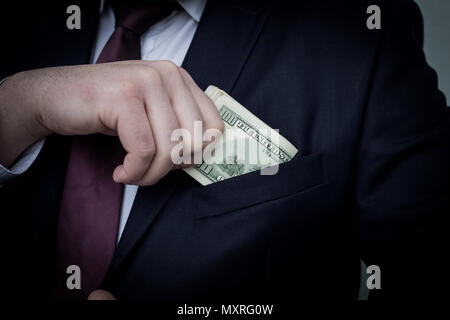 Un homme d'affaires affiche une somme d'argent, le met dans sa poche de costume Banque D'Images