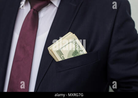 Un homme d'affaires affiche une somme d'argent, le met dans sa poche de costume Banque D'Images