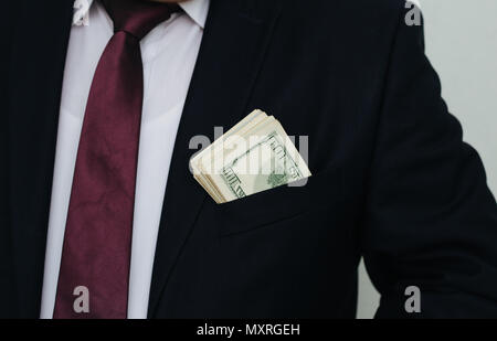 Un homme d'affaires affiche une somme d'argent, le met dans sa poche de costume Banque D'Images