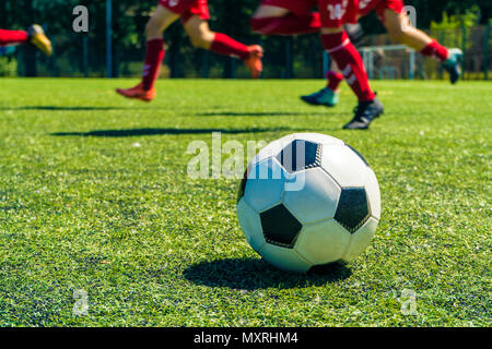 Hors focus shot de ballons de soccer et des jambes de joueurs de football lors d'une session d'entraînement de football sur terrain de soccer naturel vert. Banque D'Images