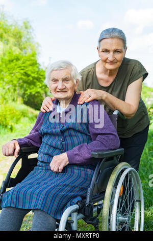 Personnes âgées woman sitting in wheelchair with middle aged fille passer du temps de qualité piscine Banque D'Images