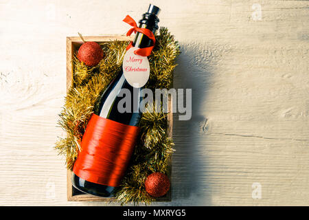 Photo de bouteille de vin avec la carte dans la case avec tinsel Banque D'Images