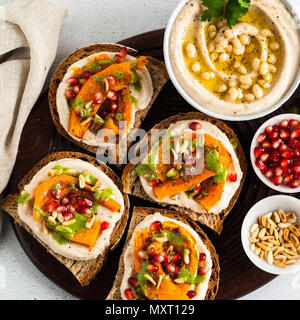 Délicieux avec du hoummos bruschettes, au four et au pesto de roquette de citrouille sur la table des aliments végétaliens. Banque D'Images