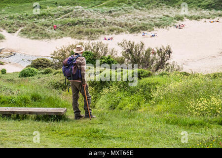 A mature walker et permanent en profitant de la vue sur Porth Joke Polly Joke sur West Pentire à Newquay en Cornouailles. Banque D'Images