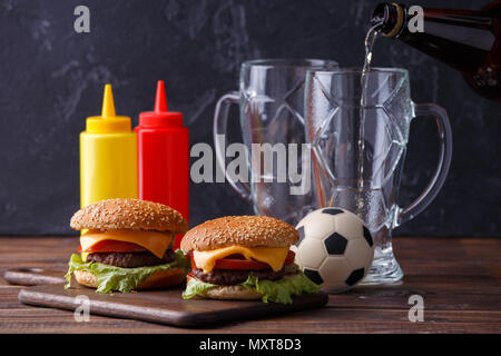 Photo de deux hamburgers, lunettes, ballon de soccer, ketchup Banque D'Images