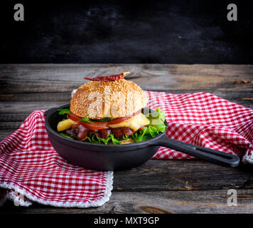 Burger avec un meatball et légumes dans un rond noir poêle en fonte, copy space Banque D'Images