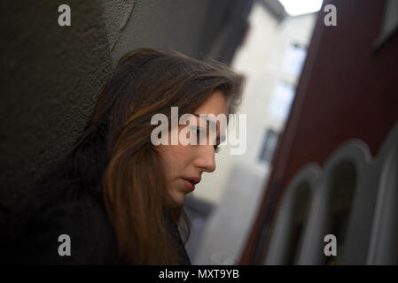 Vue de profil d'une jeune femme occidentale riche appuyé contre un mur dans une petite ruelle dans le centre-ville de Zurich Banque D'Images
