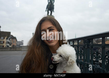 Portrait d'une jeune femme occidentale riches transporter son chien caniche blanc dans la ville de Zurich Banque D'Images