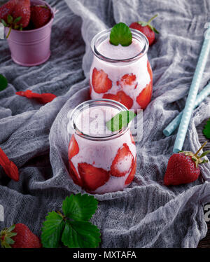 Le yaourt avec des fraises fraîches dans un bocal en verre sur une serviette textile gris, vue du dessus Banque D'Images