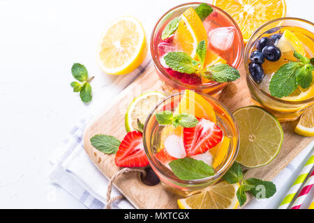La limonade avec fraises, framboises et bleuets à l'orange, lime et citron dans les verres sur blanc. Banque D'Images