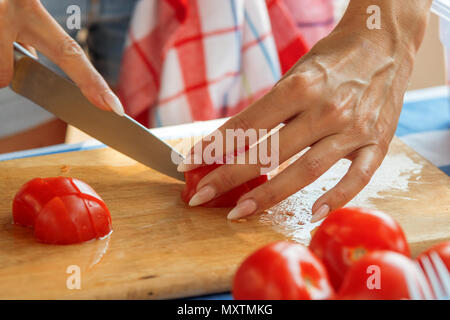 Mains femme tomate rouge tranchant sur la planche à découper en bois. Côtelettes Chef paradise de pommes pour une salade de légumes. Street Food Festival. Marché de l'alimentation. Banque D'Images