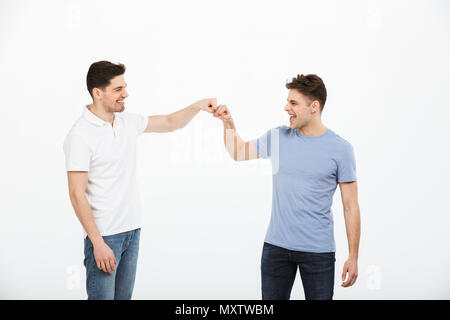 Portrait de deux jeunes hommes heureux isolé donnant fist bump sur fond blanc Banque D'Images