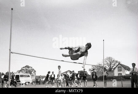 1960, tableau historique de l'écolier secondaire faisant le saut à un événement sportif du comté de l'école inter-jour, Dorset, England, UK. Banque D'Images