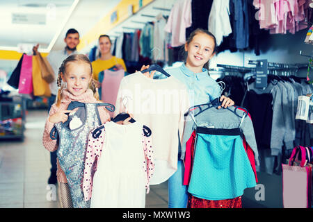 Deux sœurs avec les parents satisfaits de vos achats au magasin de vêtements pour enfants Banque D'Images