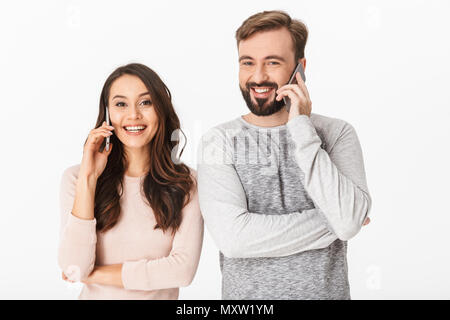 Image jeune couple aimant isolated over white wall background parler par les téléphones mobiles. Banque D'Images