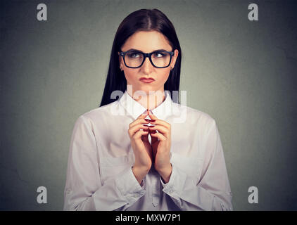 Jeune fille dans les verres sly tenant la main et à la recherche jusqu'en pensées de vengeance et de jalousie Banque D'Images