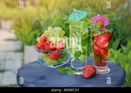 Les raisins, menthe boisson detox dans un récipient en verre avec fraise verre sur une table en bois sur une journée ensoleillée Banque D'Images