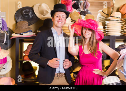 Heureux que la femme et l'homme d'essayer sur la mode chapeaux dans le shopping mall Banque D'Images