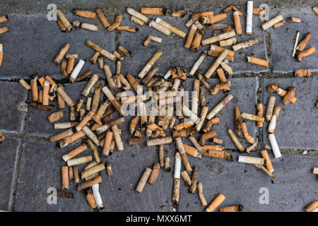 Un grand nombre de mégots jetés ou mégots jetés sur le sol, sur le trottoir. L'abandon de détritus et les fumeurs de jeter les ordures sur la rue. Banque D'Images