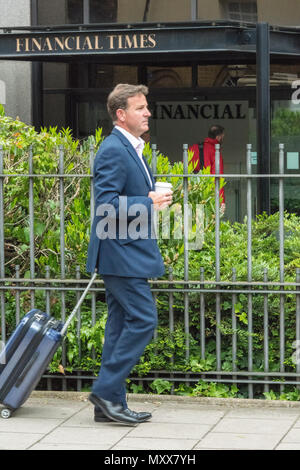 Un homme d'affaires en tirant un rouleau le long de cas ou l'exécution d'un sac passé le Financial Times Building dans le centre de Londres. Businessman with suitcase à Londres. Banque D'Images