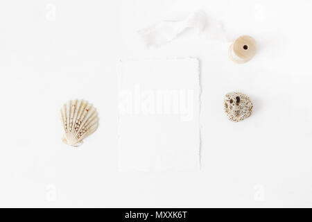 Marine d'été, bureau, papeterie de mariage modèle de scène. Carte de voeux papier coton blanc, de coquillages, de galets pierres et des bobine de ruban de soie, w Banque D'Images