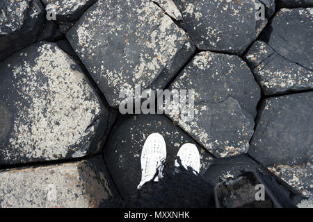 Portrait de jambes en blanc sur les pierres de basalte noir chaussures, Chaussée des Géants, en Irlande du Nord Banque D'Images