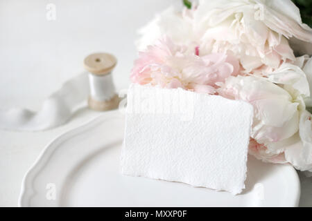 Mariage ou anniversaire lumineux maquette papeterie scène avec un papier fait à la main carte de vœux, assiette de porcelaine, le tiroir de ruban de soie et de fleurs de pivoine rose un Banque D'Images