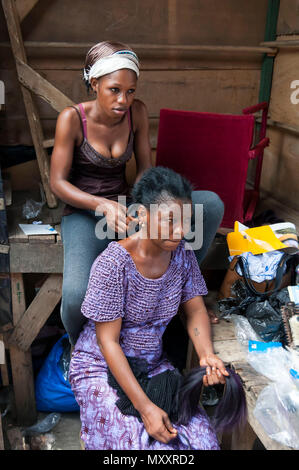 Tressage de cheveux africains originaux femme ivoirienne - visite d'une coiffure à l'Abidjan marché. Abidjan, Côte d'Ivoire (Ivory Coast), en Afrique, en avril 2013. Banque D'Images