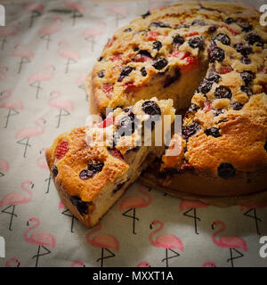 Gros plan d'une des tranches de gâteau aux fraises et framboises sur une nappe décorée avec des flamants roses. Format carré. Banque D'Images