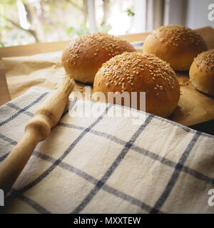 Vue de dessus des pains de sésame sur une planche en bois avec un chiffon blanc à rayures cuisine et d'un pinceau. Format carré. Banque D'Images