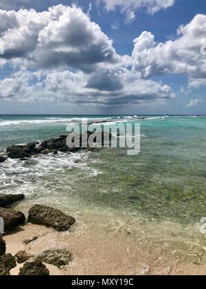 Panorama pittoresque de l'idyllique plage de Welches, Oistins La Barbade (Caraïbes) avec de grandes pierres noires / les roches, le sable blanc et une mer turquoise Banque D'Images