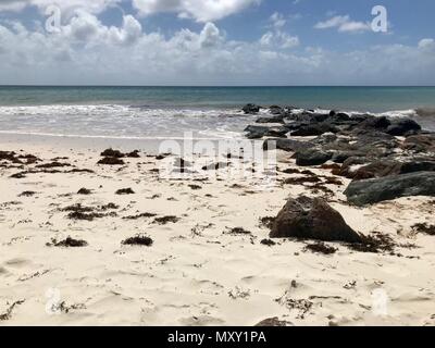 Pittoresque idyllique plage de la Barbade (île des Caraïbes des Antilles) avec de grandes pierres noires, du sable blanc et une mer turquoise avec un ciel bleu clair Banque D'Images