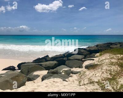 Pittoresque idyllique plage de la Barbade (île des Caraïbes des Antilles) avec de grandes pierres noires, du sable blanc et une mer turquoise avec un ciel bleu clair Banque D'Images